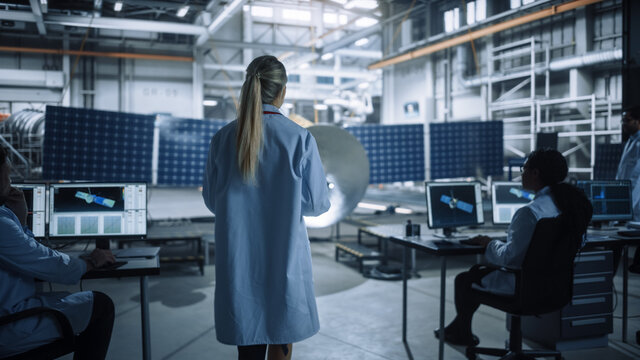 Female Engineer Uses Tablet Computer while Working on Satellite Construction. Aerospace Agency Manufacturing Facility: Scientists Build, Assemble Spacecraft for Space Exploration, Observation Mission