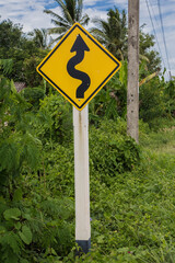 Road sign curved reminds the motorists and vehicles while driving with yellow sign reflecting light to be visible at night at the roadway in countryside of Thailand