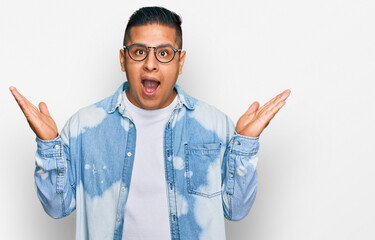 Young latin man wearing casual clothes and glasses celebrating victory with happy smile and winner...