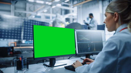 Female Engineer uses Green Screen Computer to Analyse Satellite. Aerospace Agency Manufacturing Facility: Scientists Develop, Assemble Spacecraft for Space Exploration Mission. Over Shoulder