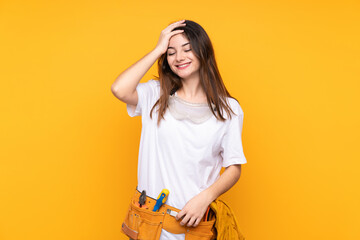 Young electrician woman over isolated on yellow background laughing