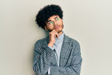 Young african american man with afro hair wearing casual clothes  glasses thinking concentrated about doubt with finger on chin and looking up wondering