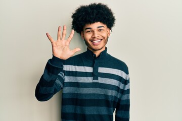 Young african american man with afro hair wearing casual clothes showing and pointing up with fingers number five while smiling confident and happy.