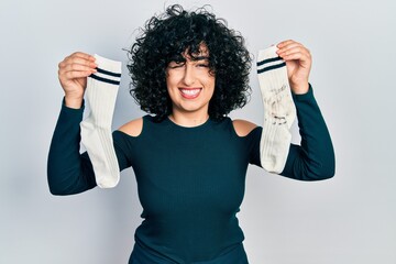Young middle east woman holding socks winking looking at the camera with sexy expression, cheerful...