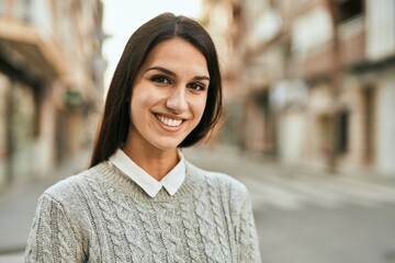 Young hispanic woman smiling happy standing at the city.