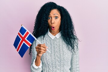 Middle age african american woman holding france flag scared and amazed with open mouth for surprise, disbelief face