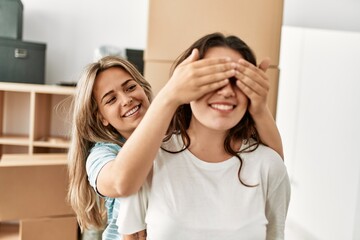 Fototapeta premium Girl surprising her girlfriend covering eyes at new home.