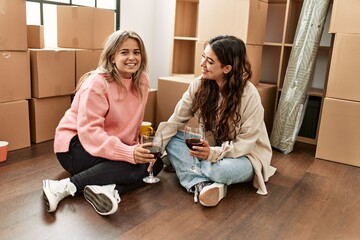 Young couple smiling happy toasting with red wine at new home