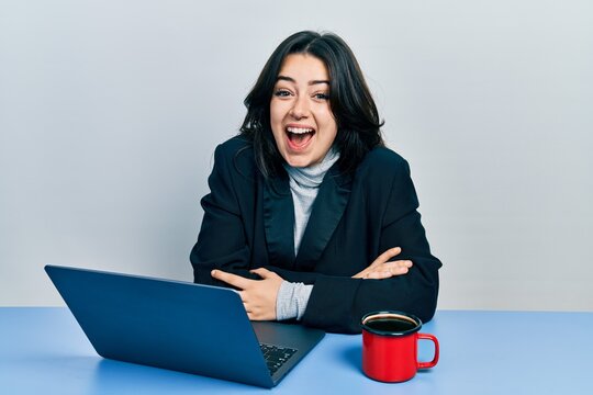 Beautiful hispanic business woman with arms crossed gesture at the office celebrating crazy and amazed for success with open eyes screaming excited.