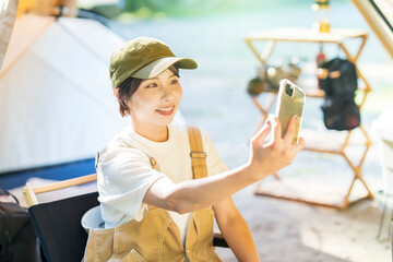 Fototapeta premium ソロキャンプイメージ・スマートフォンで自撮りする女性 
