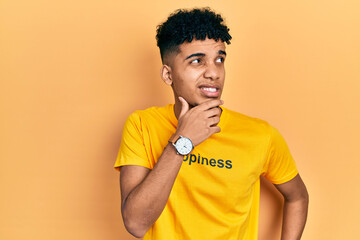 Young african american man wearing t shirt with happiness word message thinking worried about a question, concerned and nervous with hand on chin