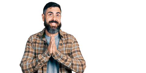 Fototapeta na wymiar Hispanic man with beard wearing casual shirt begging and praying with hands together with hope expression on face very emotional and worried. begging.