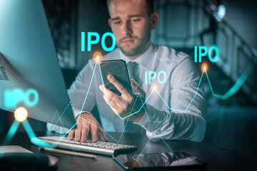 Businessman in casual wear using smart phone to optimize IPO strategy at corporate fund. Financial chart hologram over modern office background at night time