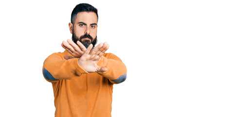 Hispanic man with beard wearing casual winter sweater rejection expression crossing arms doing negative sign, angry face