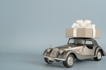 Toy antique car with gift box  on grey background with place for text.Happy birthday, valentine's day, weddings card concept.