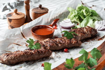 Kebab with sauce and greens on a plate