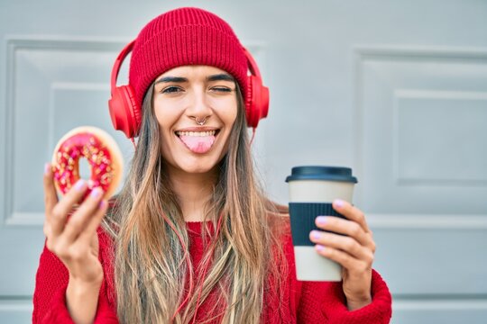 Young hispanic woman having breakfast using headphones at the city.