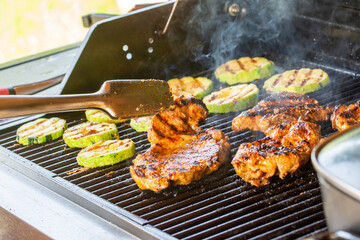 Juicy chicken steaks and grilled zucchini slices prepared on a modern gas garden grill