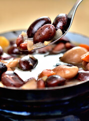 Kidney bean soup with large beans in an old enamel pot. Close-up. Vertical photo.