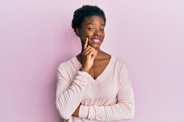 Young african american girl wearing casual clothes smiling looking confident at the camera with crossed arms and hand on chin. thinking positive.