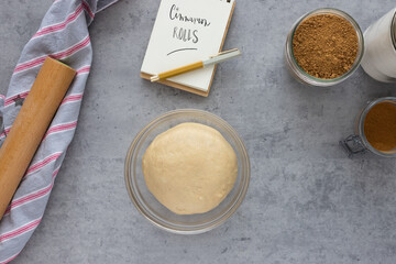 Homemade cinnamon roll dough inside a crystal bowl surrounded by jars full of vanilla powder.