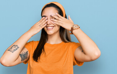 Young hispanic woman wearing casual clothes covering eyes with hands smiling cheerful and funny. blind concept.