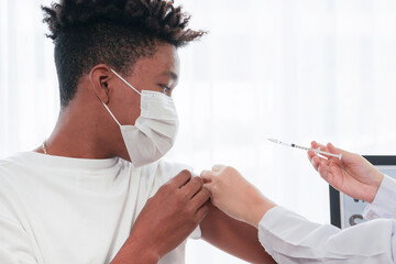 Portrait of African-American man looking at while getting covid vaccine in clinic or hospital, with...