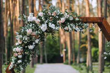 Element of a wedding wooden arch decorated with natural flowers at a ceremony in the forest.