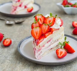 Dessert, sliced sponge cake with custard, fresh strawberries and whipped cream on a gray concrete background. Swedish cuisine.