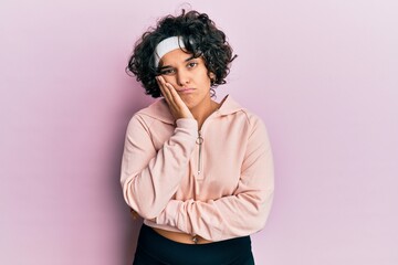 Fototapeta na wymiar Young hispanic woman with curly hair wearing sportswear thinking looking tired and bored with depression problems with crossed arms.