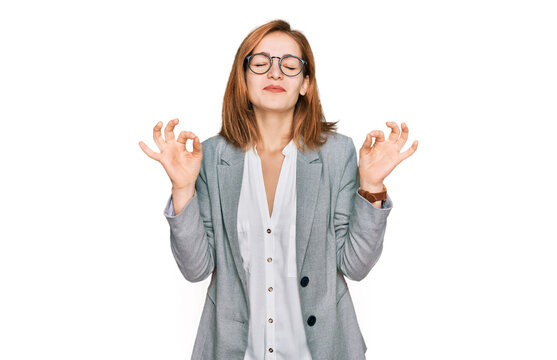 Young caucasian woman wearing business style and glasses relaxed and smiling with eyes closed doing meditation gesture with fingers. yoga concept.