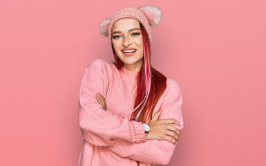 Young caucasian woman wearing casual clothes and wool cap happy face smiling with crossed arms looking at the camera. positive person.