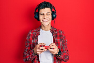 Young hispanic man playing video game holding controller smiling with a happy and cool smile on face. showing teeth. © Krakenimages.com