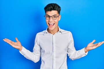 Young hispanic man wearing casual clothes and glasses celebrating victory with happy smile and winner expression with raised hands