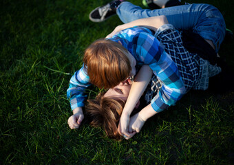 Boy and girl teenagers are fighting on the grass in nature