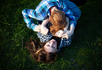 Boy and girl teenagers are fighting on the grass in nature