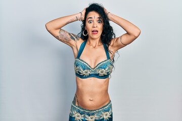 Obraz premium Young woman wearing bindi and traditional belly dance clothes crazy and scared with hands on head, afraid and surprised of shock with open mouth