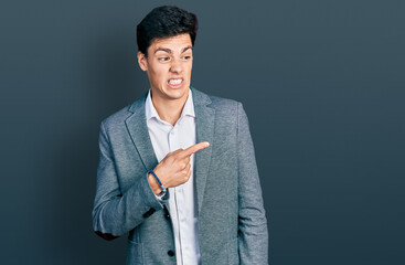 Young hispanic man wearing business clothes pointing aside worried and nervous with forefinger,...
