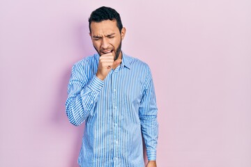 Hispanic man with beard wearing casual blue shirt feeling unwell and coughing as symptom for cold or bronchitis. health care concept.