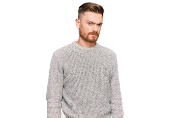 Young redhead man wearing casual winter sweater skeptic and nervous, frowning upset because of...