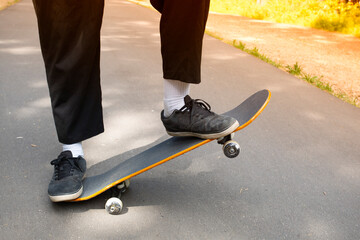 A young man rides a skateboard in the park in the summer.