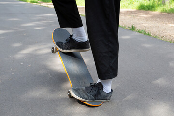 A young man rides a skateboard in the park in the summer.