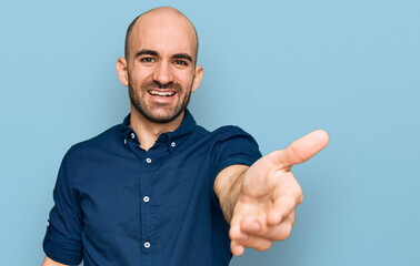 Naklejka premium Young hispanic man wearing casual clothes smiling friendly offering handshake as greeting and welcoming. successful business.