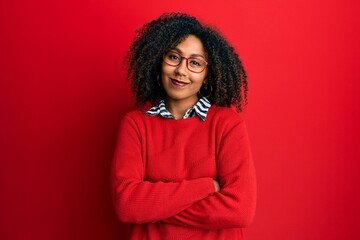 Fototapeta premium Beautiful african american woman with afro hair wearing sweater and glasses happy face smiling with crossed arms looking at the camera. positive person.