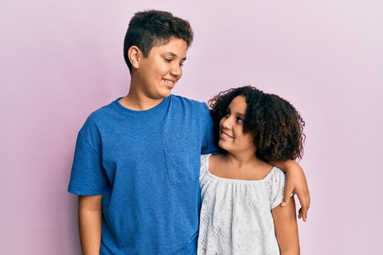 Young hispanic family of brother and sister wearing casual clothes together smiling looking to the side and staring away thinking.