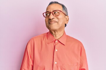 Obraz premium Middle age indian man wearing casual clothes and glasses smiling looking to the side and staring away thinking.