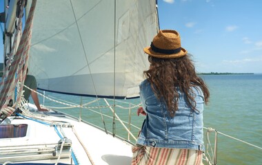 Fototapeta premium Happy young woman sailing, enjoying cruising on sailboat on a sunny summer day.