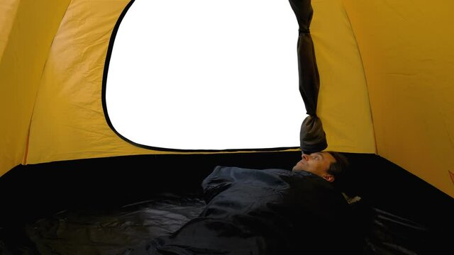 Travaller in sleeping bag is waking up and looking outside the tent, View from tourist tent, Full HD footage with alpha transparency channel isolated on white background