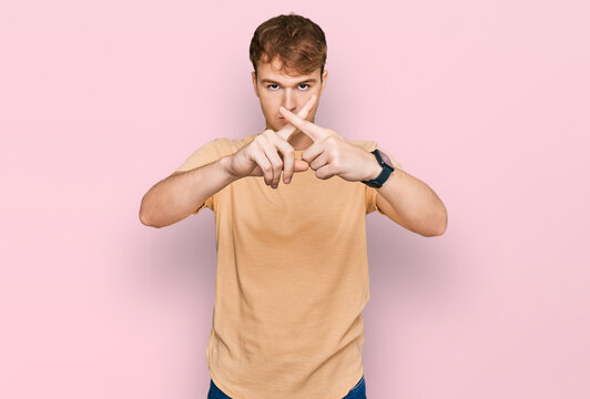 Young caucasian man wearing casual clothes rejection expression crossing fingers doing negative sign