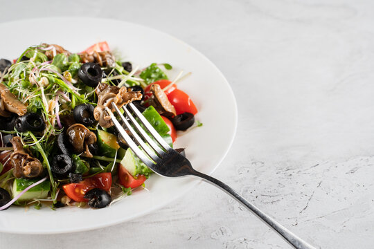 Green salad with escargot grape snails on white background. French gourmet cuisine.